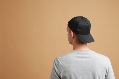 Photo of Man in stylish baseball cap on beige background, back view. Mockup for design