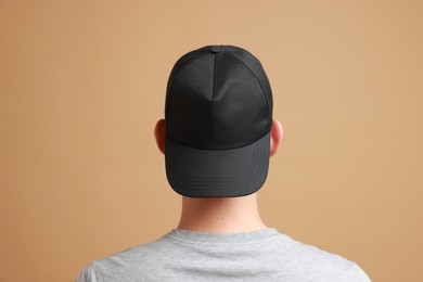 Photo of Man in stylish baseball cap on beige background, back view. Mockup for design