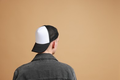 Photo of Man in stylish baseball cap on beige background, back view. Mockup for design