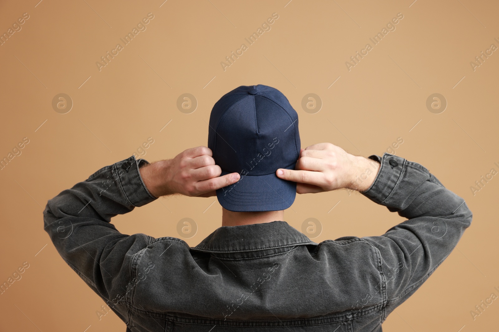 Photo of Man in stylish baseball cap on beige background, back view. Mockup for design