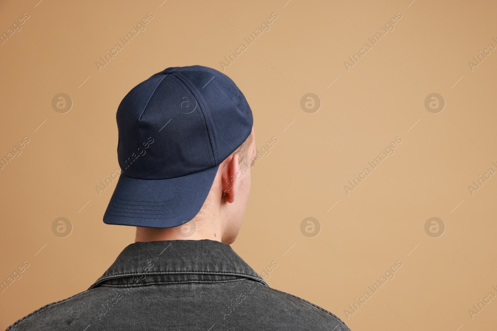 Photo of Man in stylish baseball cap on beige background, back view. Mockup for design