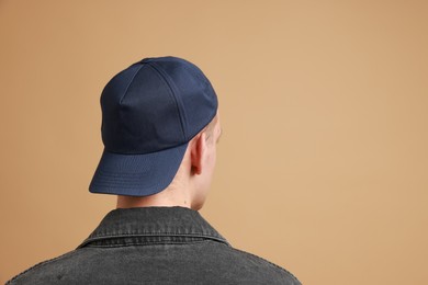 Photo of Man in stylish baseball cap on beige background, back view. Mockup for design