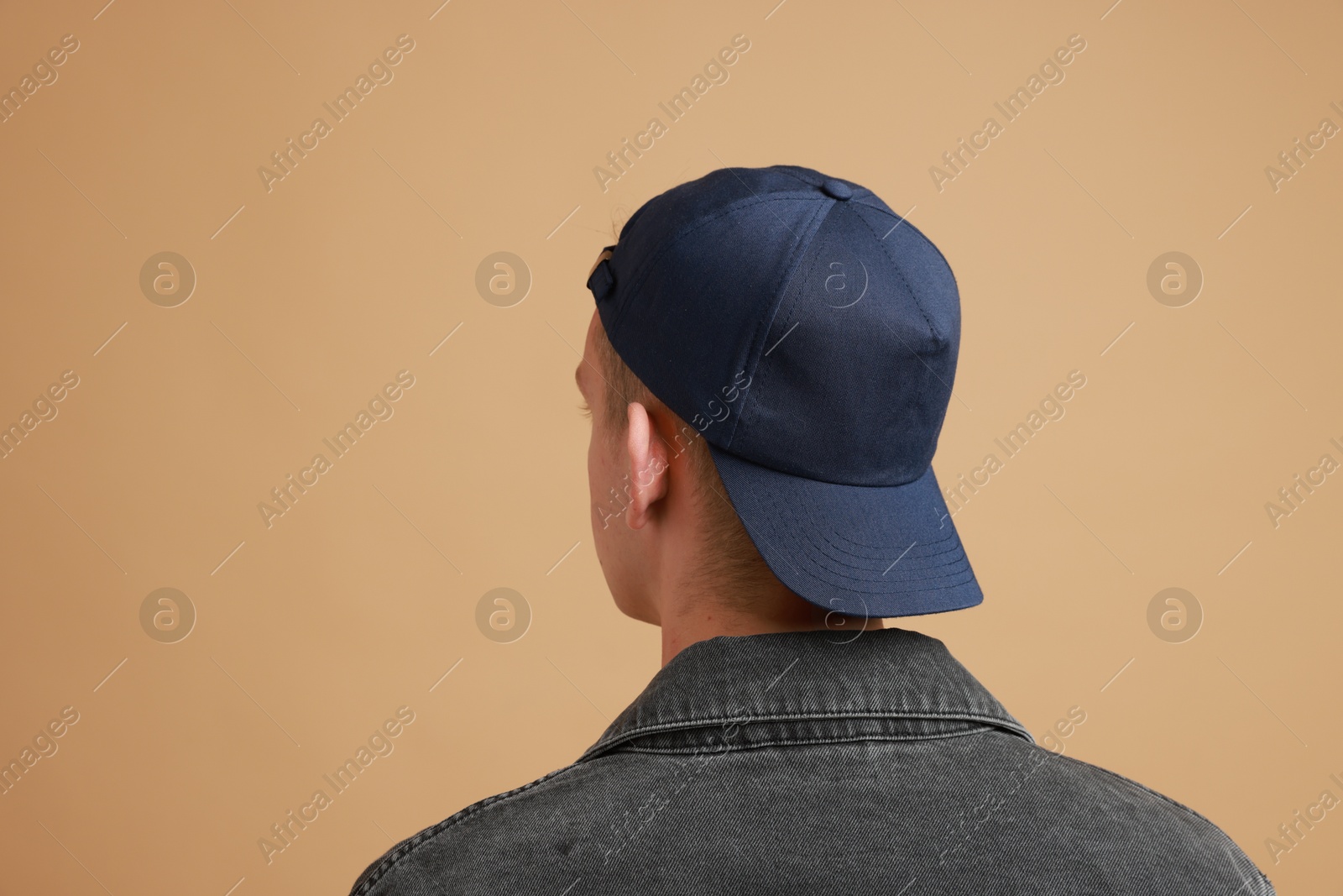 Photo of Man in stylish baseball cap on beige background, back view. Mockup for design