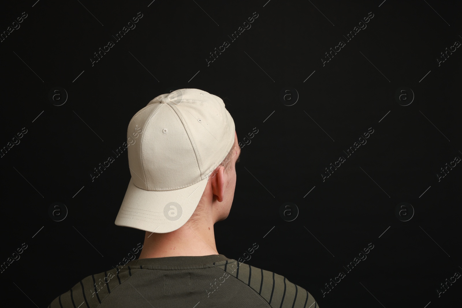 Photo of Man in stylish baseball cap on black background, back view. Mockup for design