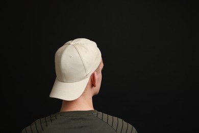 Photo of Man in stylish baseball cap on black background, back view. Mockup for design