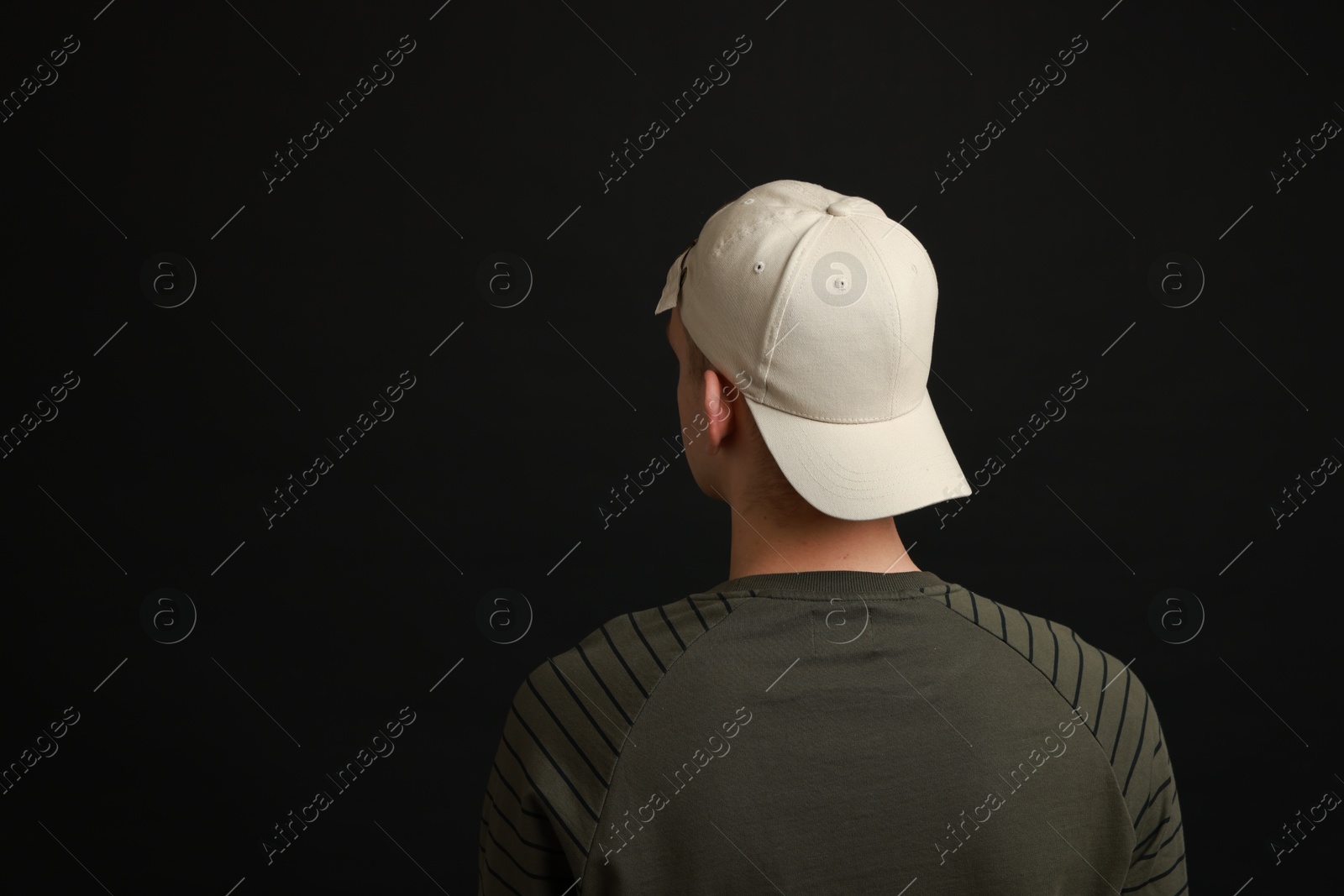 Photo of Man in stylish baseball cap on black background, back view. Mockup for design