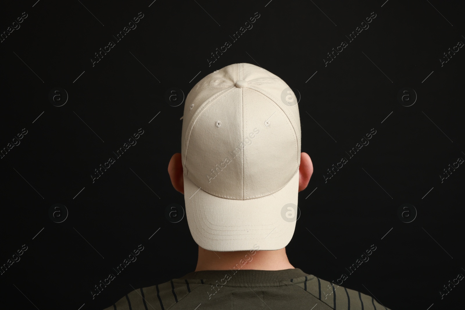 Photo of Man in stylish baseball cap on black background, back view. Mockup for design