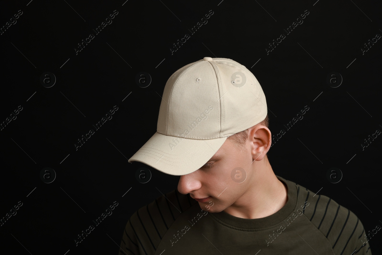 Photo of Man in stylish baseball cap on black background. Mockup for design