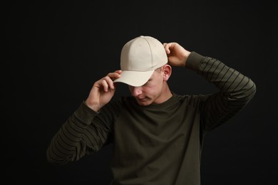 Photo of Man in stylish baseball cap on black background. Mockup for design