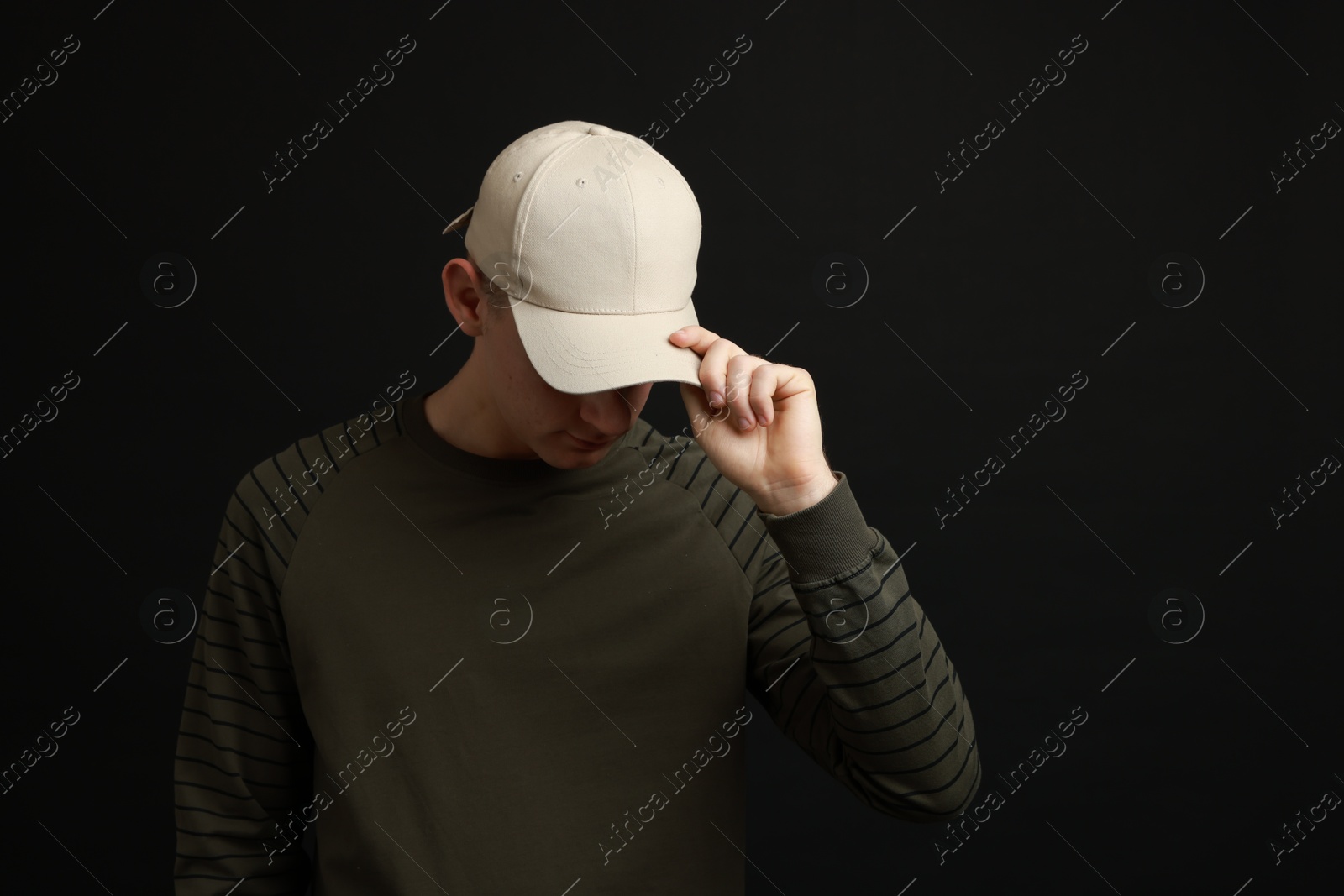 Photo of Man in stylish baseball cap on black background. Mockup for design