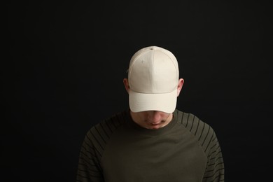 Photo of Man in stylish baseball cap on black background. Mockup for design