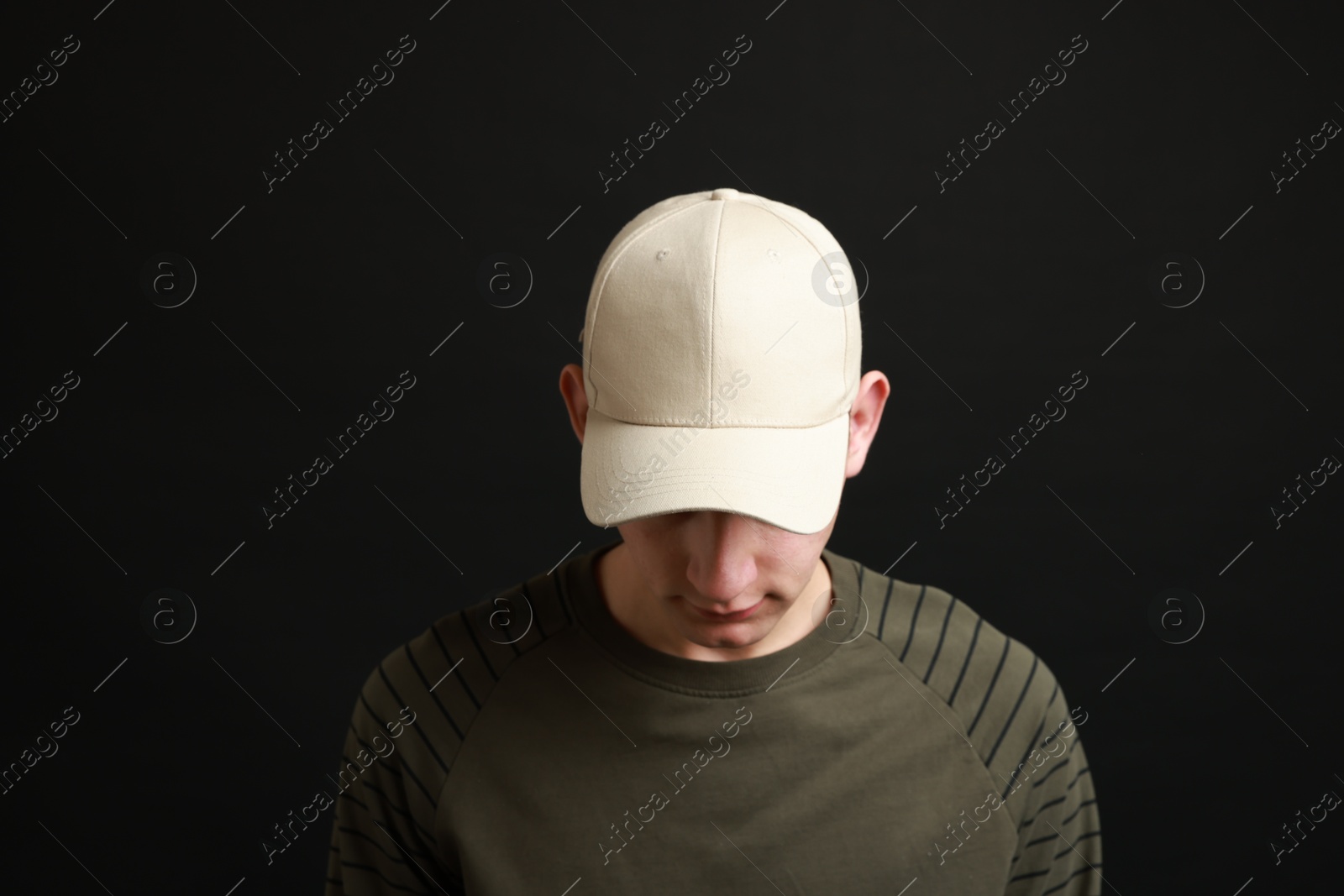 Photo of Man in stylish baseball cap on black background. Mockup for design