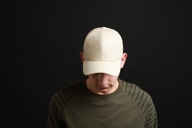 Photo of Man in stylish baseball cap on black background. Mockup for design