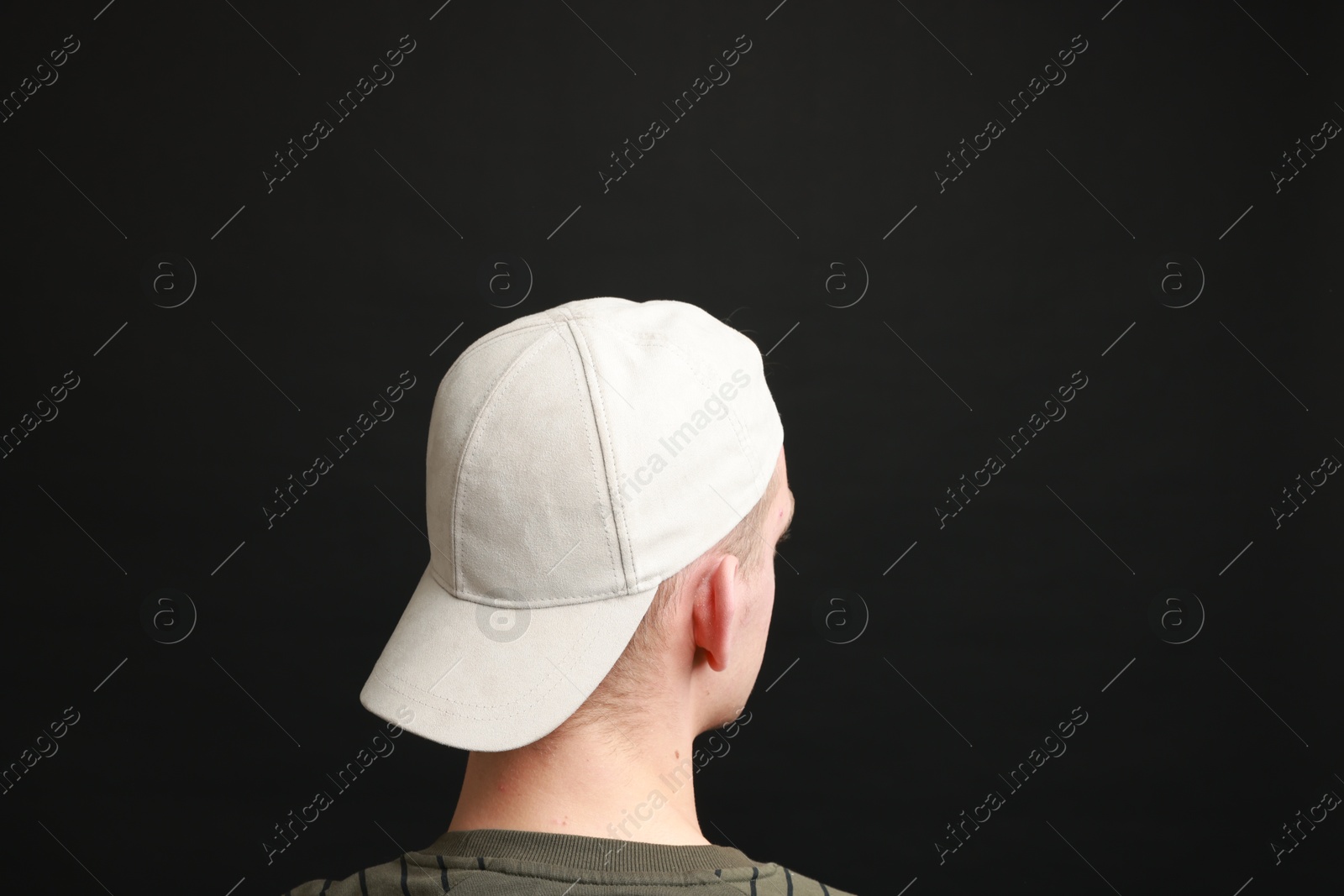 Photo of Man in stylish baseball cap on black background, back view. Mockup for design