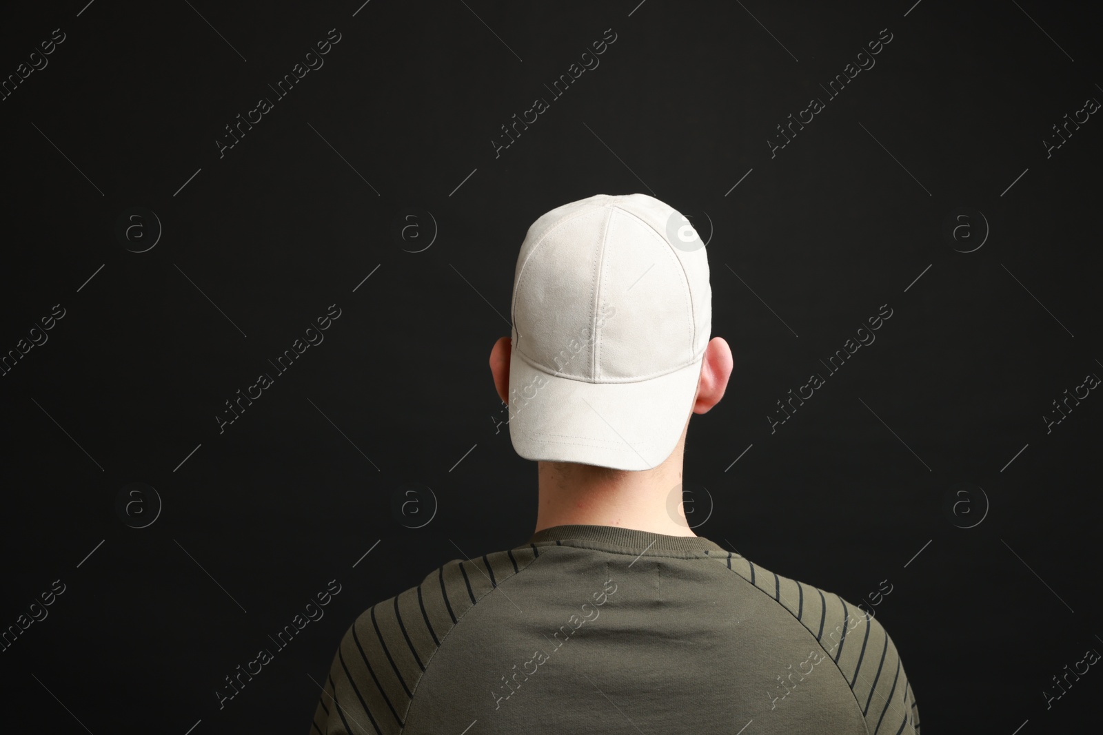 Photo of Man in stylish baseball cap on black background, back view. Mockup for design