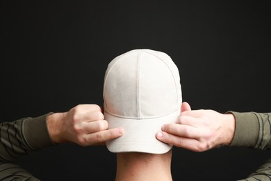 Photo of Man in stylish baseball cap on black background, back view. Mockup for design