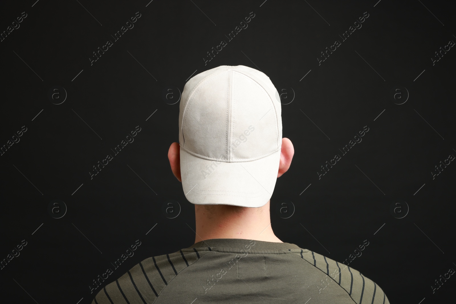 Photo of Man in stylish baseball cap on black background, back view. Mockup for design