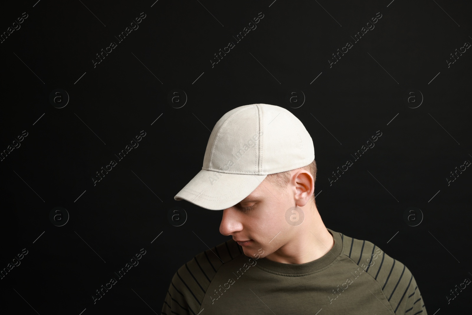 Photo of Man in stylish baseball cap on black background. Mockup for design