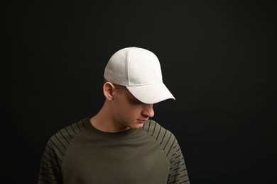 Photo of Man in stylish baseball cap on black background. Mockup for design