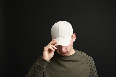 Photo of Man in stylish baseball cap on black background. Mockup for design