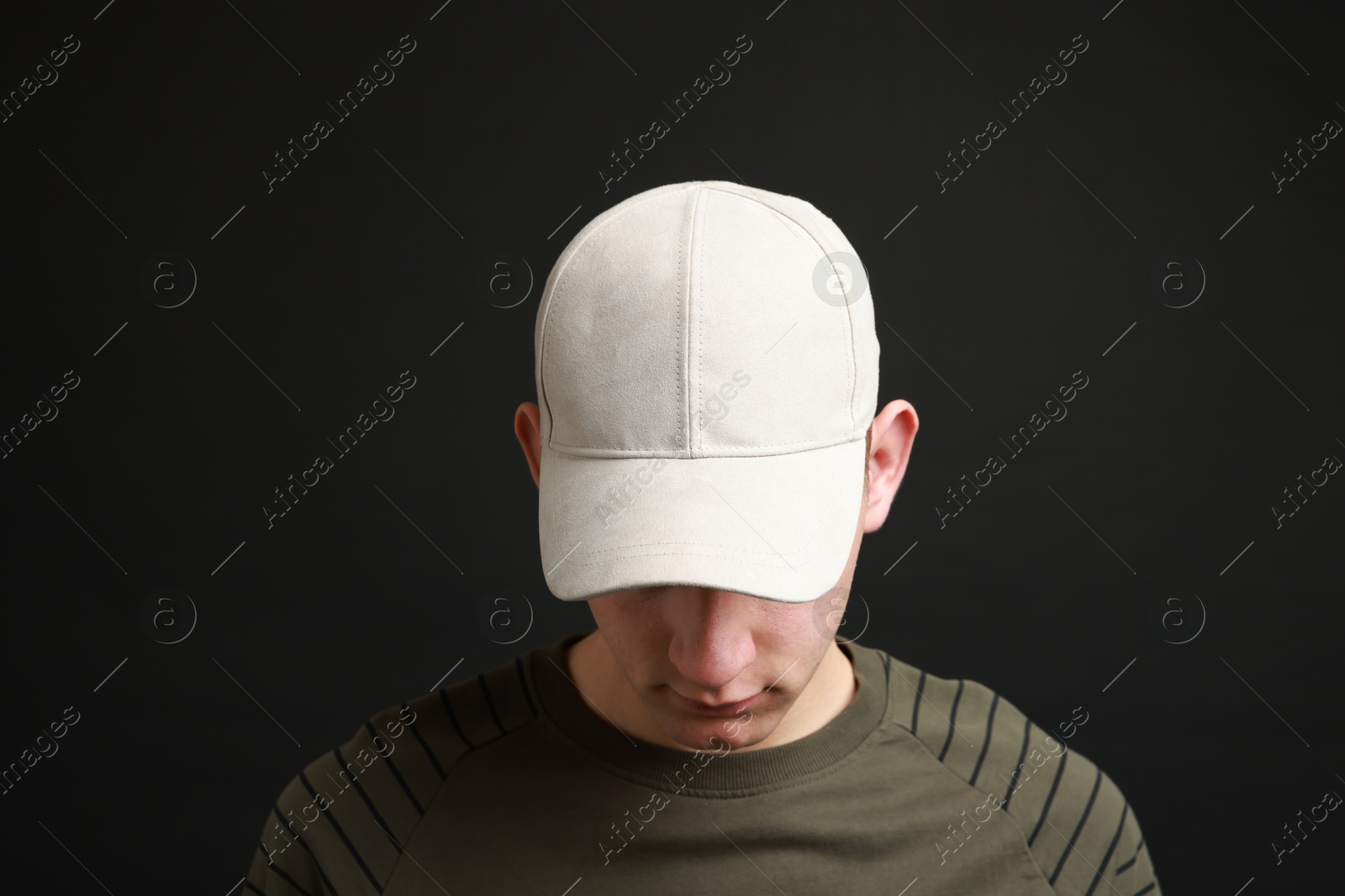 Photo of Man in stylish baseball cap on black background. Mockup for design