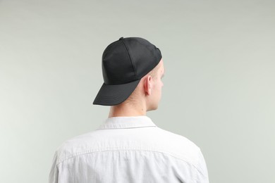 Photo of Man in stylish baseball cap on light grey background, back view. Mockup for design