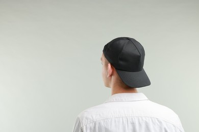 Photo of Man in stylish baseball cap on light grey background, back view. Mockup for design