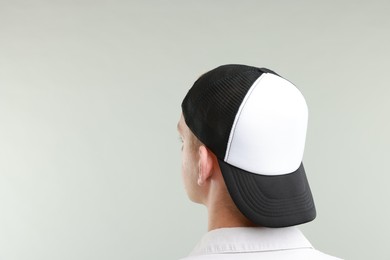 Photo of Man in stylish baseball cap on light grey background, back view. Mockup for design