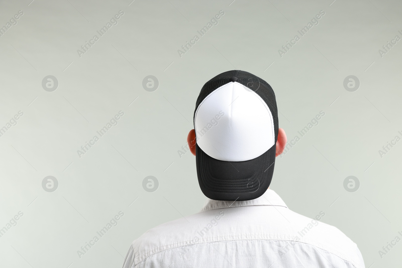 Photo of Man in stylish baseball cap on light grey background, back view. Mockup for design