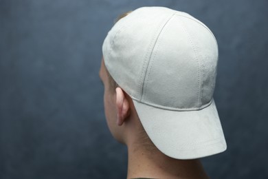 Photo of Man in stylish baseball cap on blurred grey background, closeup. Mockup for design