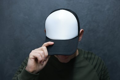 Photo of Man in stylish baseball cap near grey wall. Mockup for design