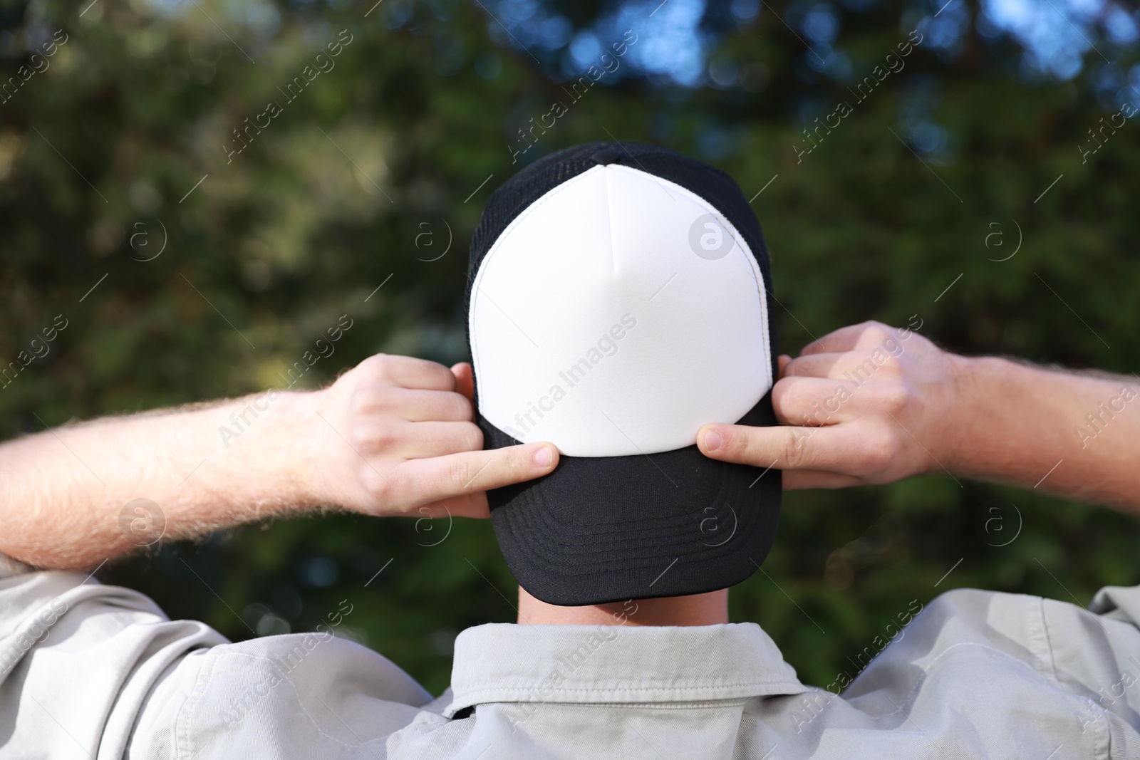 Photo of Man in stylish baseball cap outdoors, back view. Mockup for design