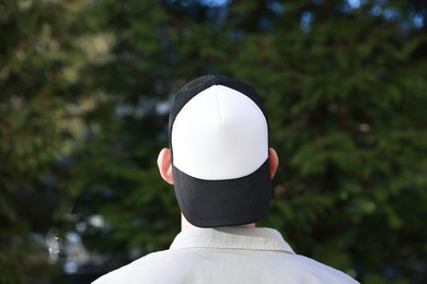 Photo of Man in stylish baseball cap outdoors, back view. Mockup for design