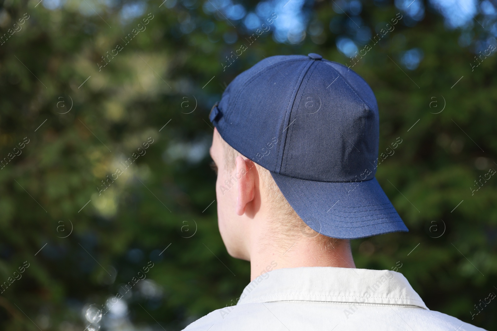 Photo of Man in stylish baseball cap outdoors, back view. Mockup for design