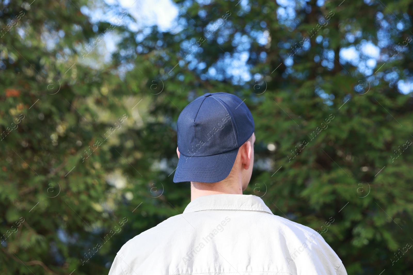 Photo of Man in stylish baseball cap outdoors, back view. Mockup for design