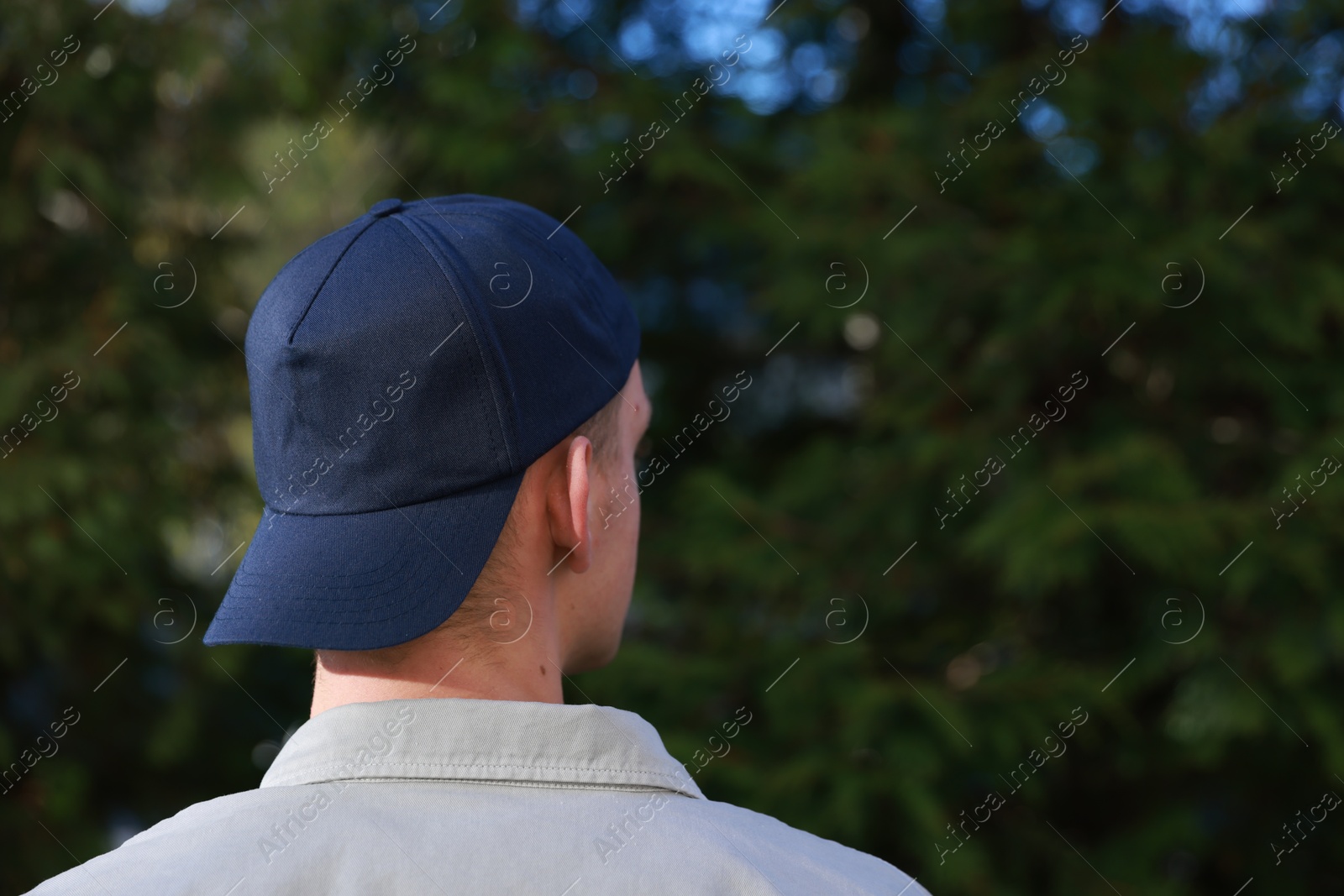 Photo of Man in stylish baseball cap outdoors, back view. Mockup for design