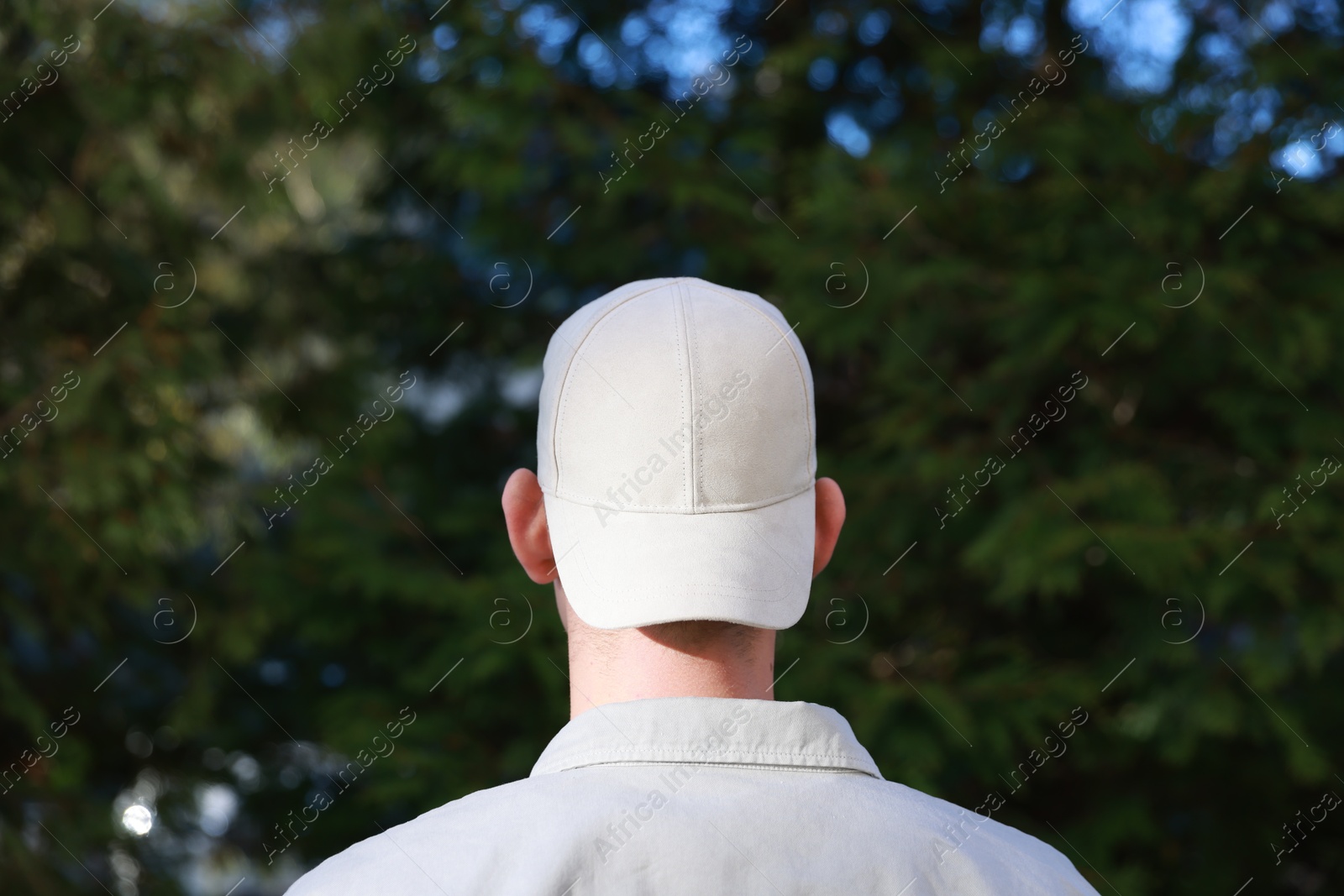 Photo of Man in stylish baseball cap outdoors, back view. Mockup for design