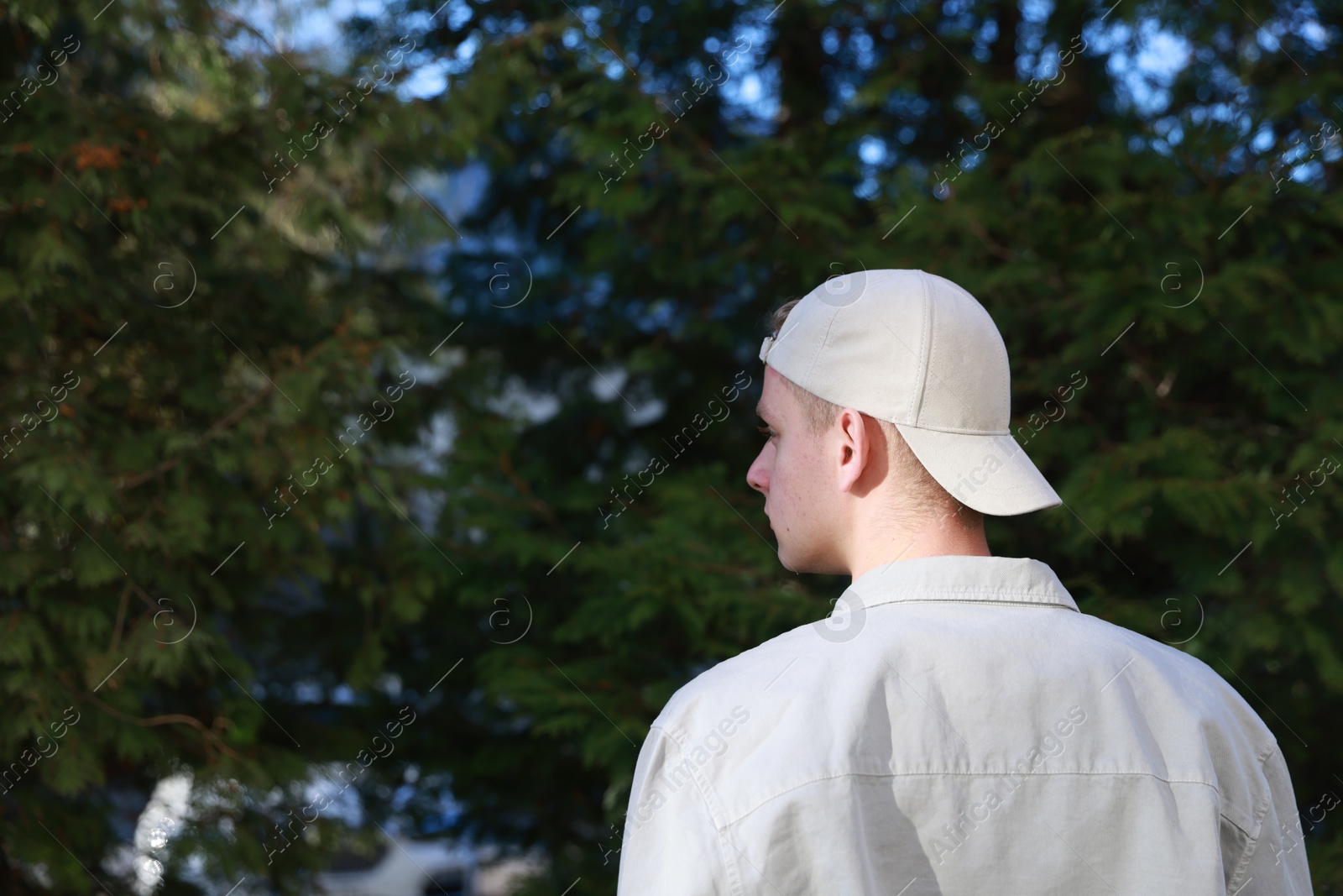 Photo of Man in stylish baseball cap outdoors, back view. Mockup for design