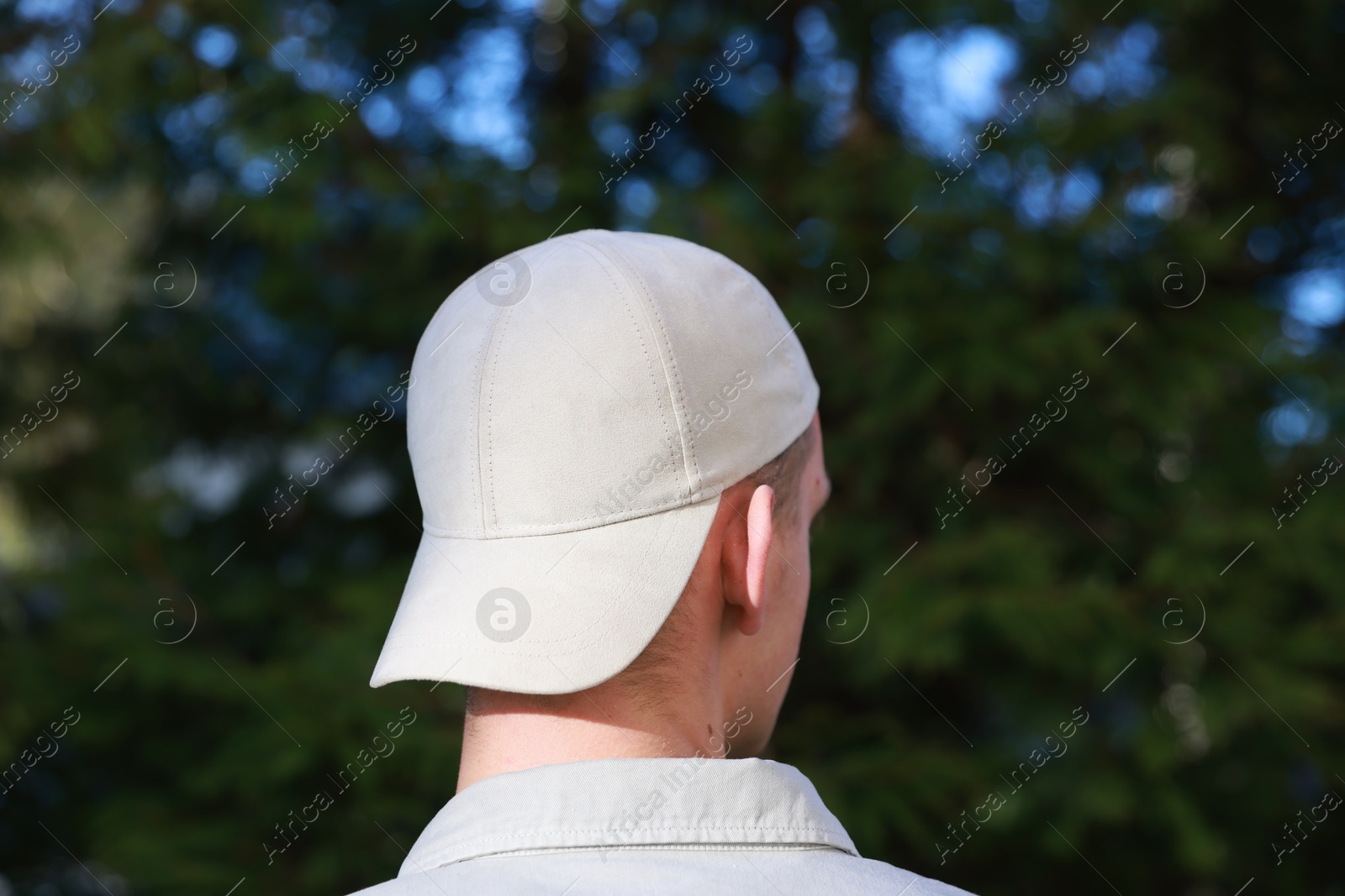 Photo of Man in stylish baseball cap outdoors, back view. Mockup for design