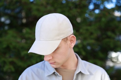 Man in stylish baseball cap outdoors. Mockup for design