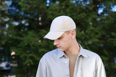 Photo of Man in stylish baseball cap outdoors. Mockup for design