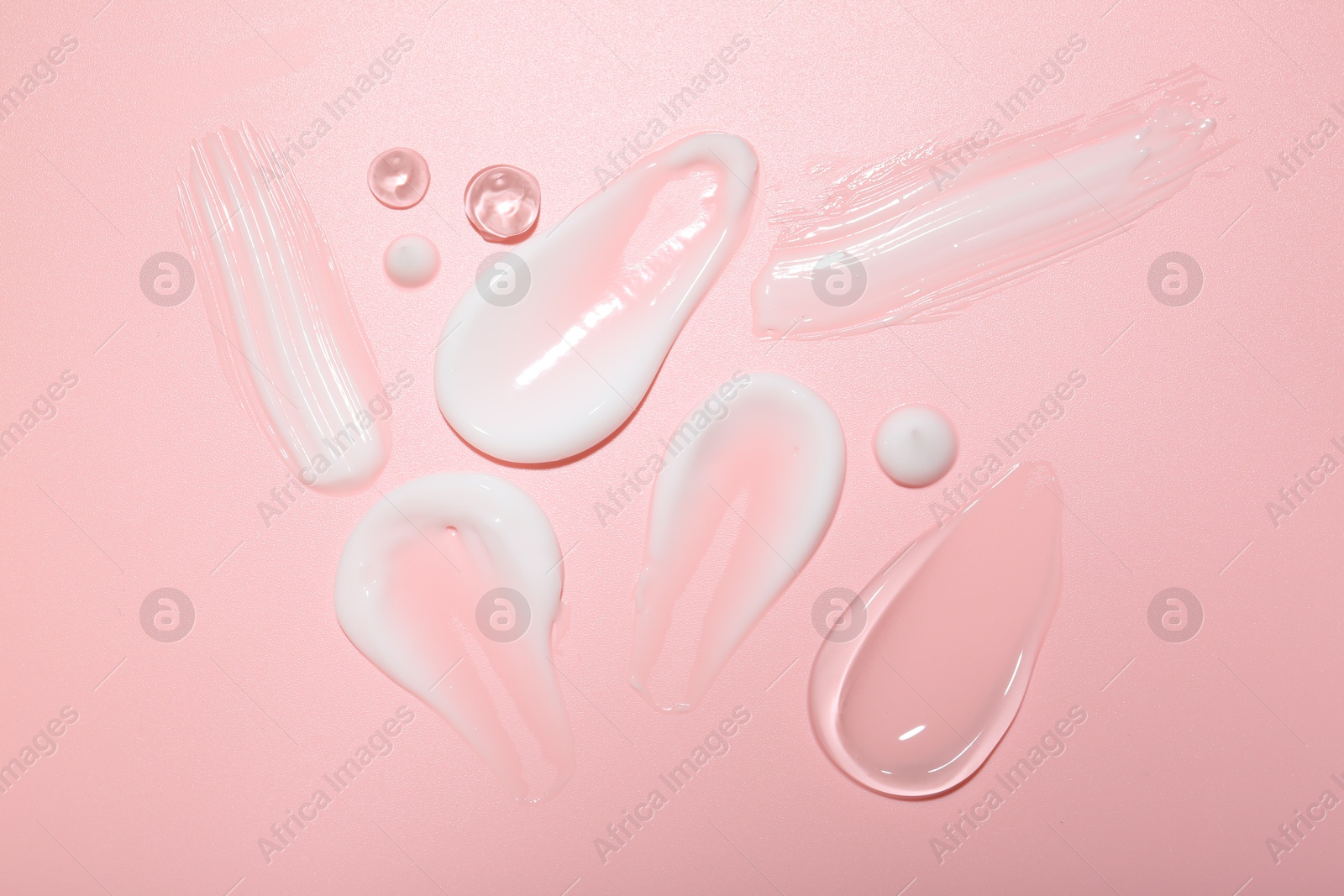 Photo of Cream and gel samples on pink background, top view