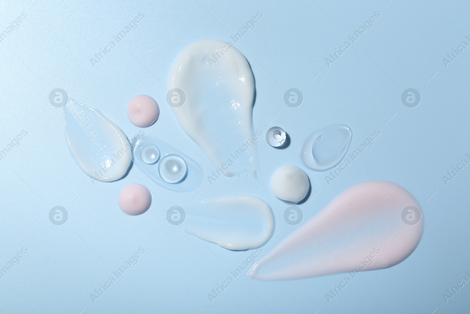 Photo of Cream and gel samples on light blue background, top view