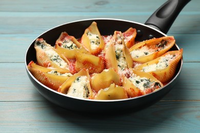 Photo of Delicious shell pasta stuffed with ricotta and spinach on blue wooden table, closeup