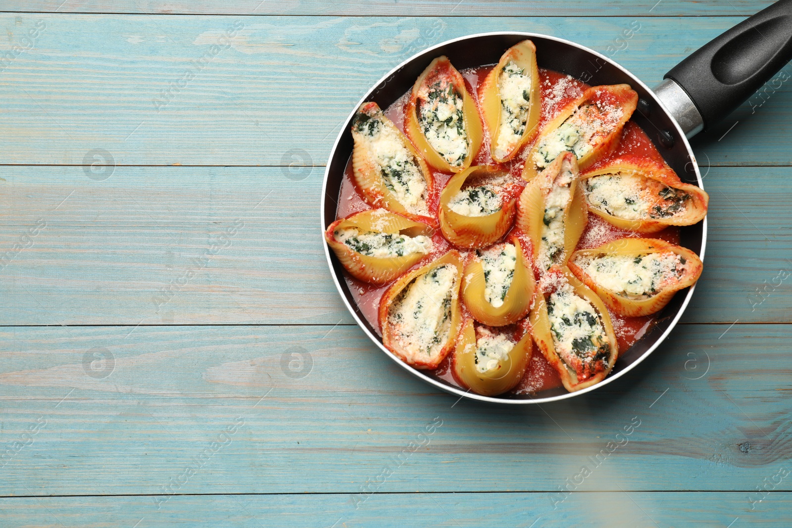 Photo of Delicious shell pasta stuffed with ricotta and spinach on blue wooden table, top view. Space for text