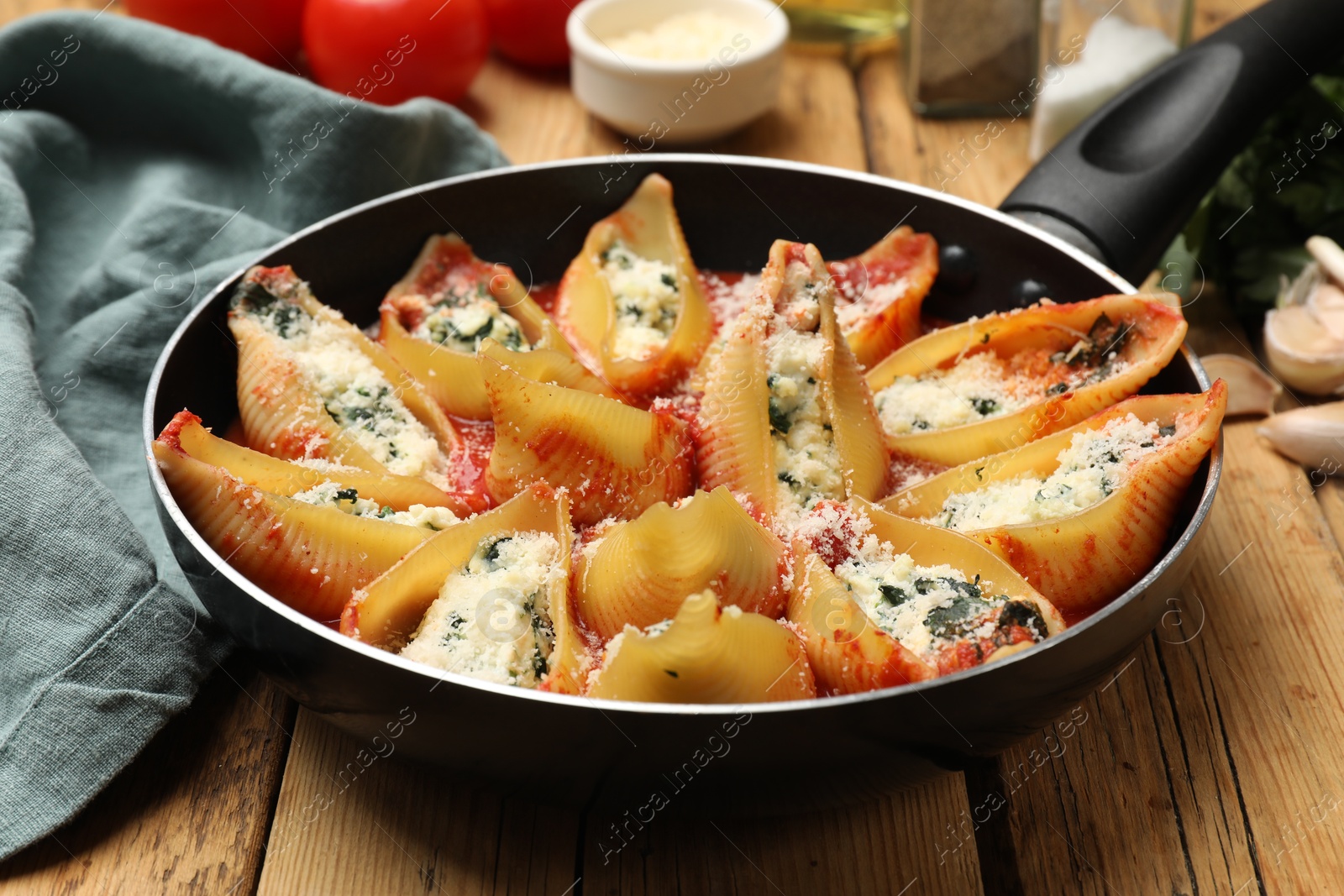 Photo of Delicious shell pasta stuffed with ricotta and spinach served on wooden table, closeup