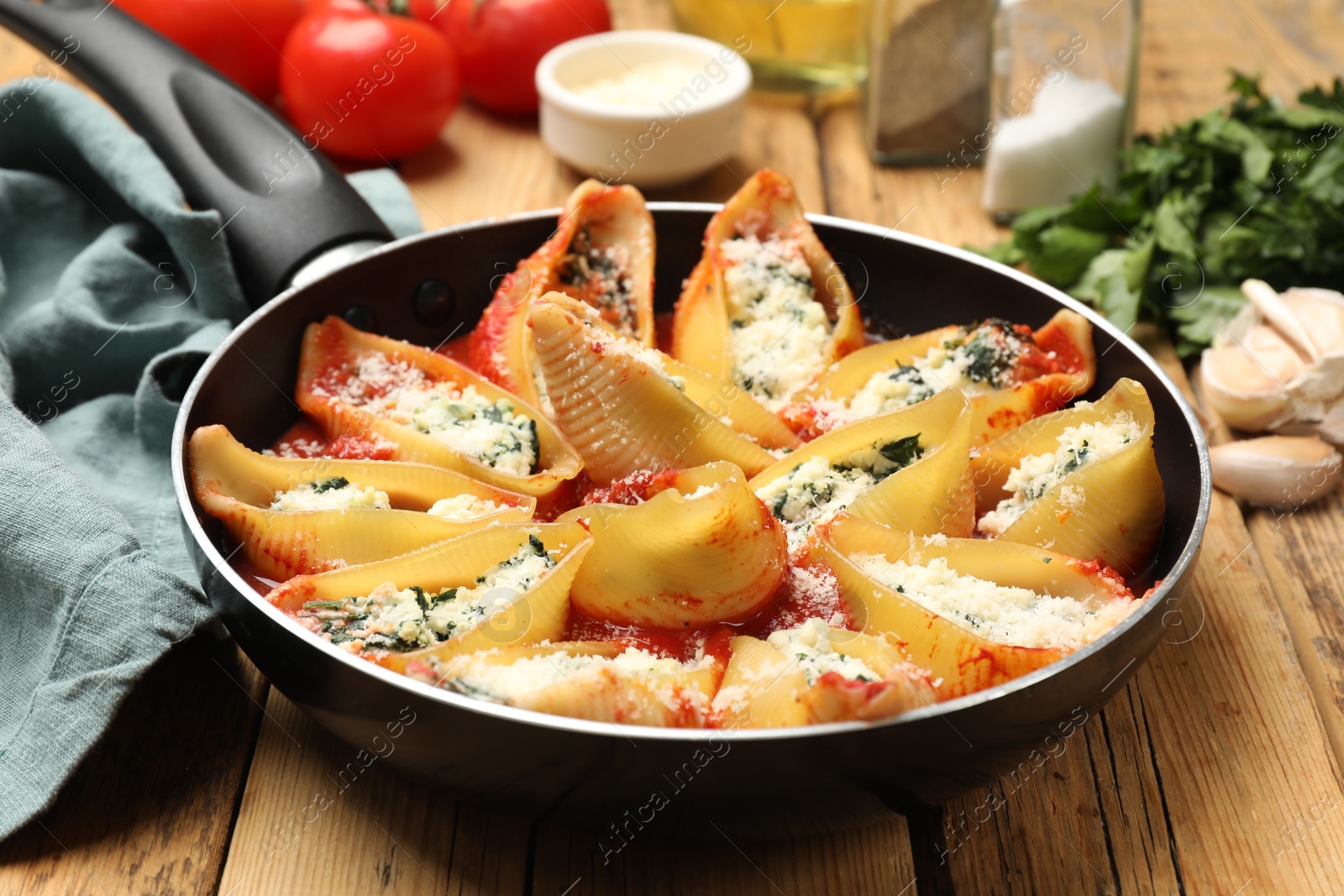 Photo of Delicious shell pasta stuffed with ricotta and spinach served on wooden table, closeup