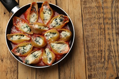 Photo of Delicious shell pasta stuffed with ricotta and spinach on wooden table, top view. Space for text