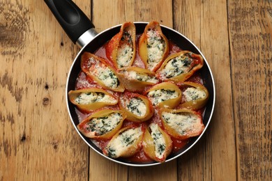 Photo of Delicious shell pasta stuffed with ricotta and spinach on wooden table, top view