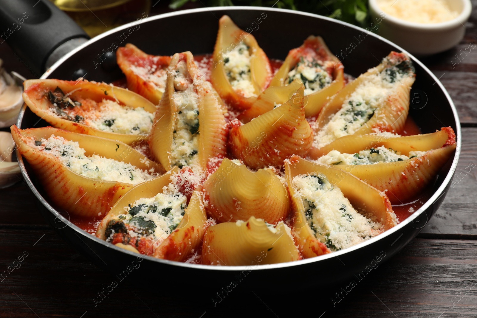 Photo of Delicious shell pasta stuffed with ricotta and spinach served on wooden table, closeup